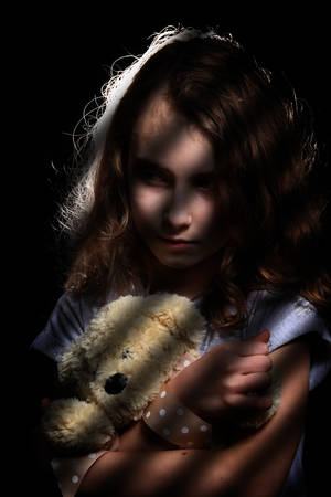 scared young girl hugs a teddy bearの写真素材