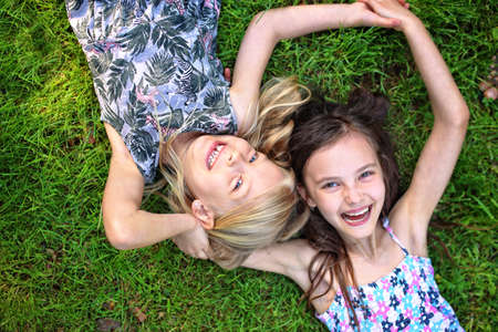 joyful friends lie on the grass and laughの写真素材