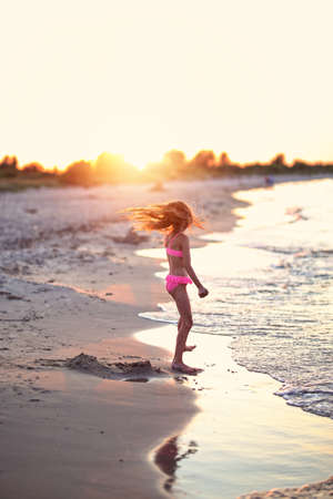 young girl in a complete costume is dancing on the beachの写真素材