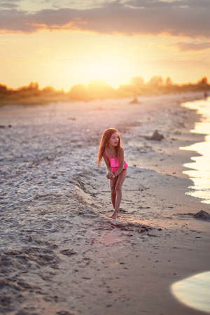 young girl in a costume is playing on the beachの写真素材