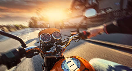 Motorcyclist drives motorbike on a sunny day on the streetの写真素材