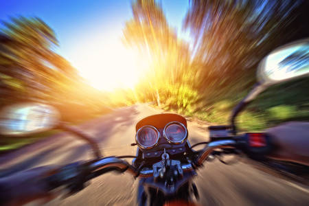 Motorcyclist drives motorbike on a sunny day on the street