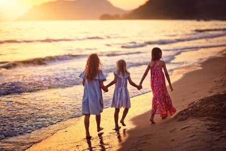 joyful friends hold hands and run on the beachの写真素材