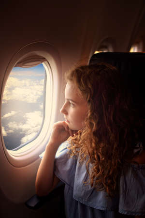 Young girls looks outside the window in planeの写真素材