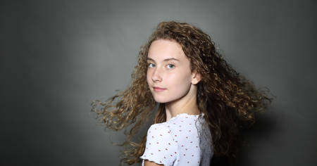 young girl in curly hair on a gray backgroundの写真素材