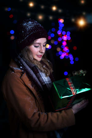 young girl holding a gift in the winter evening