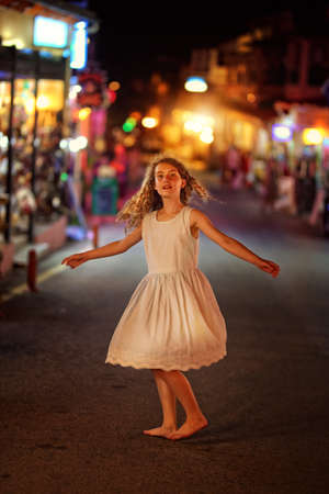 young girl dancing on the street at nightの写真素材