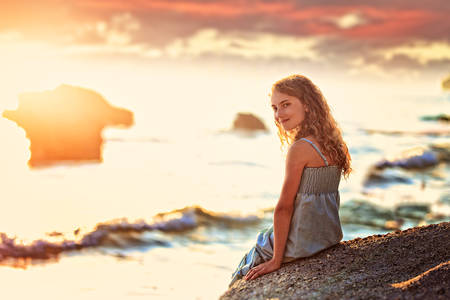 joyful and cheerful girl is sitting on the beachの写真素材
