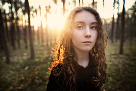 portrait of a young girl with curly hair in the forestの写真素材