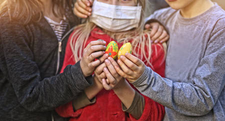 kids in masks hold an Easter eggの写真素材