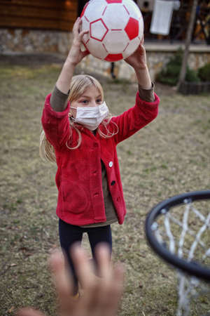 Children in the mask are playing basketball outsideの写真素材