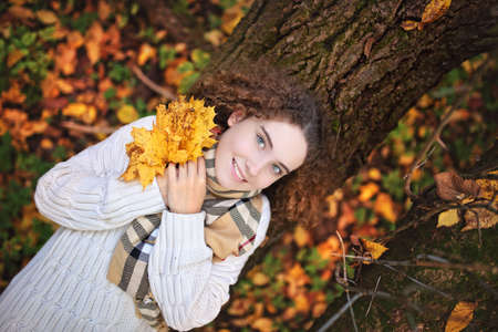 A young smiling teenage girl with curly hair on an autumn day in the parkの写真素材