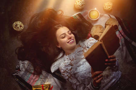 young and beautiful girl reads a book in the comfort of home