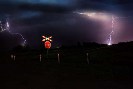 storm at night and railroad crossing stop signの写真素材