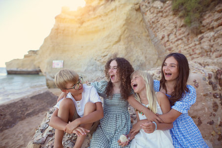 young friends are laughing on the beach by the cliffsの写真素材