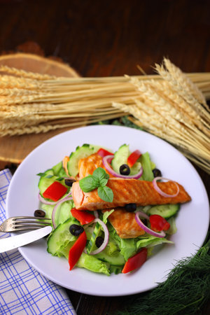 Appetizing salmon fish out of the oven with salad and olivesの写真素材