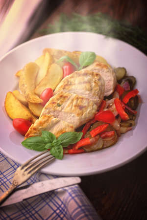 delicious grilled chicken breast served with vegetables and potatoesの写真素材