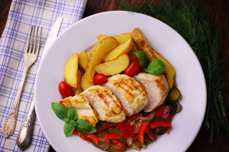 delicious grilled chicken breast served with vegetables and potatoesの写真素材