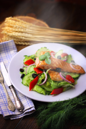 Appetizing salmon fish out of the oven with salad and olivesの写真素材