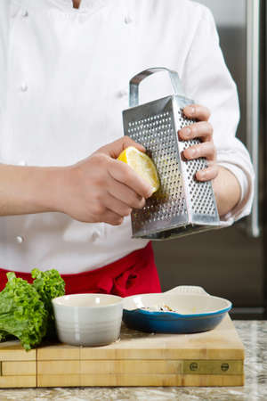 Chief is grating a lemon in the kitchenの写真素材