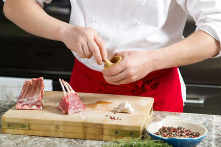 Cook chef is preparing the spices in a wooden mortar in the kitchenの写真素材