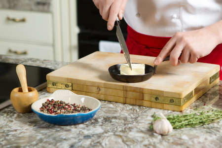 Chief cook cut the butter on the pan with the knife in the kitchen tableの写真素材