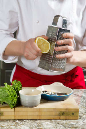 Chief is grating a lemon in the kitchenの写真素材