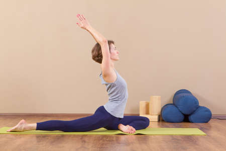 Flexible young woman stretching in gym.