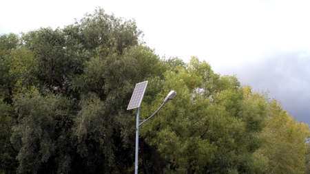 Saving technology. Green energy. Clean energy. Street lamp post with solar panel in Park with green tree and blue sky for background energy saving concept. Clean energy.の写真素材