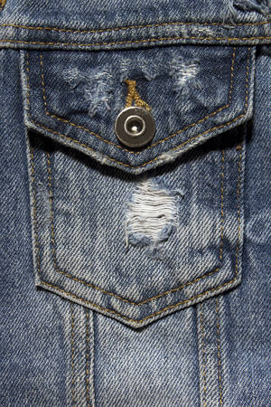 Vintage denim texture background: jacket close-up. Blue torn denim pocket. Stylish torn denim background. Closeup pocket on blue denim jean and button. Denim, fashionable jacket.の写真素材
