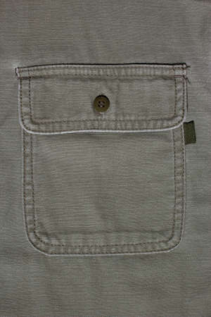 Denim background made of khaki denim textiles. On the pocket is sewn a tag for applying text or logo. Military clothing. Shirt for tourism. Military uniform.の写真素材