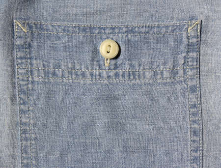 Vintage denim texture background: pocket with a button-down shirt close-up. Stylish pocket with button denim background. Closeup pocket on blue denim jean and button.の写真素材