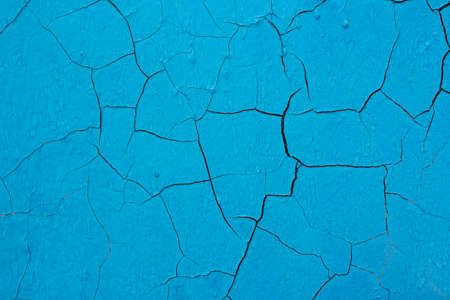 The old cracked blue paint on a wall surface. Peeling paint on wall seamless texture. Pattern of rustic blue grunge material. Vintage pattern from cracks, chips, stains for print and design.の写真素材