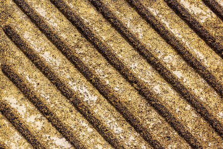 Corrugated concrete texture in yellow. Wavy concrete wall pattern. Close-up of yellow wavy surface, eliciting optical illusion. An old wavy surface on a concrete wall. Rough texture of paving slabsの写真素材