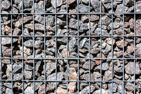 Gabion Made Of Black Stone And Metal Wire Mesh. A stone wall that uses metal and stone in harmony....