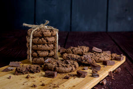 Dark chocolate cookies with chocolate chips tied with a rope on a dark wooden surfaceの写真素材