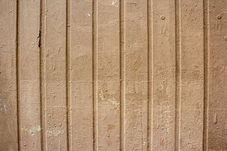 Corrugated sheet metal, badly painted with lightdo brown paint for background. Metal corrugated roofing sheet. Painting of metal surfaces for rust control. Abstract background for sites and layoutsの写真素材