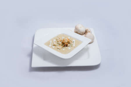 Hero Shot of a Mushroom Soup with bread crumbs, oregano on a minimal white background with a 45 degree angleの写真素材