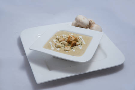 Hero Shot of a Mushroom Soup with bread crumbs, oregano on a minimal white background with a 45 degree angleの写真素材
