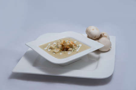 Hero Shot of a Mushroom Soup with bread crumbs, oregano on a minimal white background with a 45 degree angleの写真素材