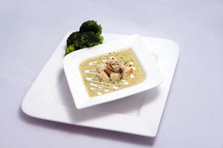 Hero Shot of a Broccoli Soup with bread crumbs, oregano on a minimal white background with a 45 degree front facing angleの写真素材