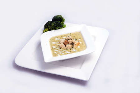 Hero Shot of a Broccoli Soup with bread crumbs, oregano on a minimal white background with a 45 degree front facing angleの写真素材