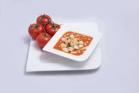 a Hero Shot of a Tomato Soup with bread crumbs, oregano on a minimal white background with a diagonal 45 angleの写真素材