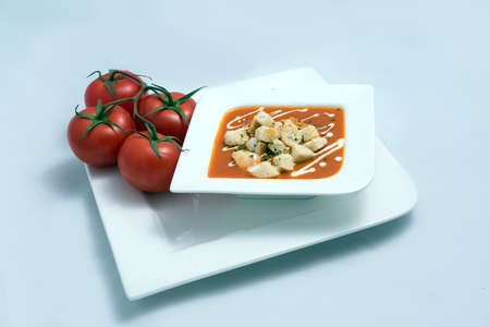 a Hero Shot of a Tomato Soup with bread crumbs, oregano on a minimal white background with a diagonal 45 angleの写真素材