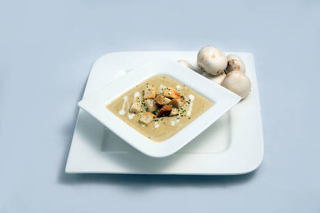 Contrasted Hero Shot of a Mushroom Soup with bread crumbs, oregano on a minimal white background with a 60 degree front facing angleの写真素材