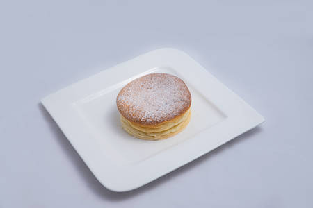 A low contrast Hero Shot of a pan cake on a plate, on a minimal white background with a diagonal 60 degree angleの写真素材