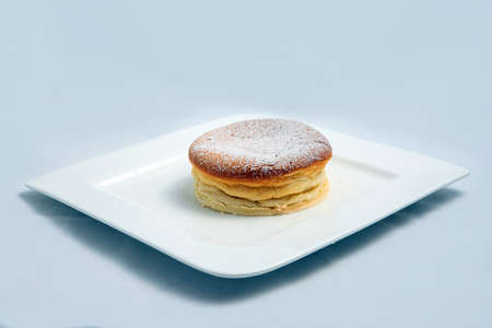A low contrast Hero Shot of a pan cake on a plate, on a minimal white background with a diagonal 60 degree angleの写真素材