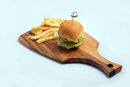 A low contrast Hero Shot of a grilled chicken slider burger, fries on a wooden platter board, on a minimal white background with a 45 degree angle from a diagonal perspectiveの写真素材