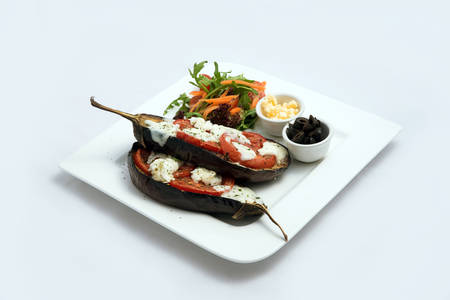 A low contrast warm Hero shot of a main course platter with grilled aubergine with buffalo cheese, tomato, olives & vegetables on the side, on a minimal white background with a 45 degree angle from diagonal perspective.の写真素材
