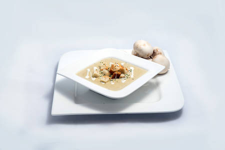 Hero Shot of a Mushroom Soup with bread crumbs, oregano on a minimal white background with a 45 degree angleの写真素材